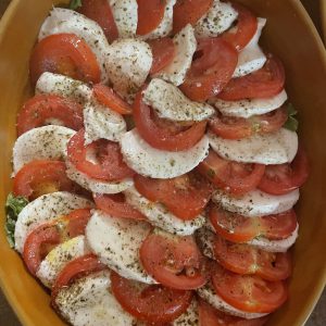 A mozzarella cheese salad with tomato slices , salt and pepper as well as olive oil.